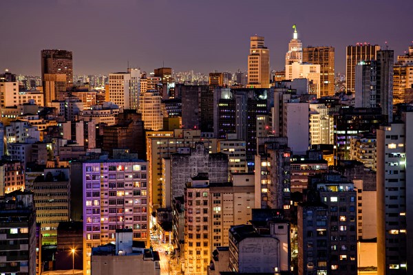 Paisagem urbana de São Paulo à noite. Vista noturna da cidade de São Paulo, com inúmeros prédios e iluminados sob um céu roxo.